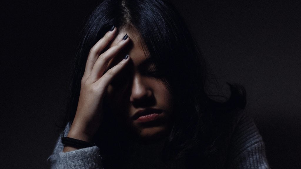 Woman in dark setting with hand covered