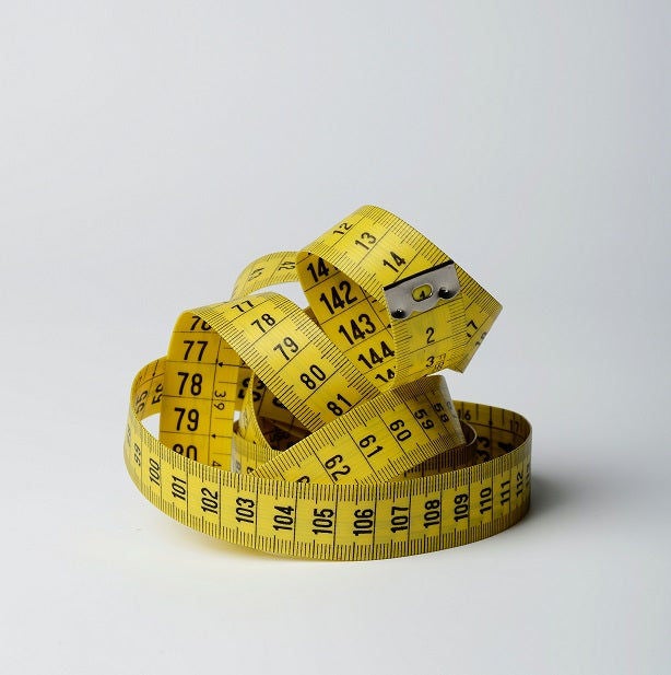 Yellow measuring tape coiled on white background