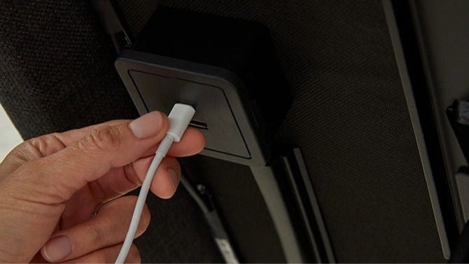 Hand plugging cable into furniture USB port