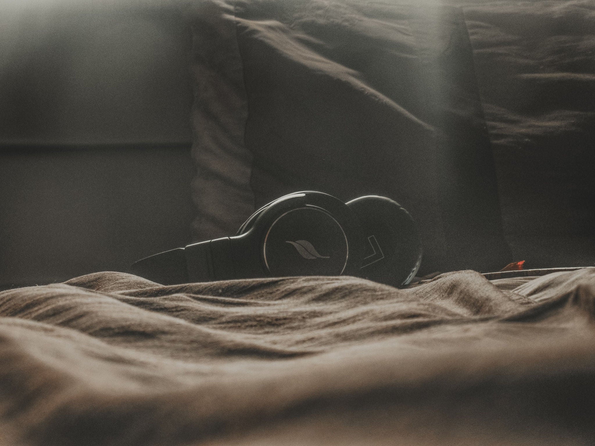 Black headphones on a cozy bed