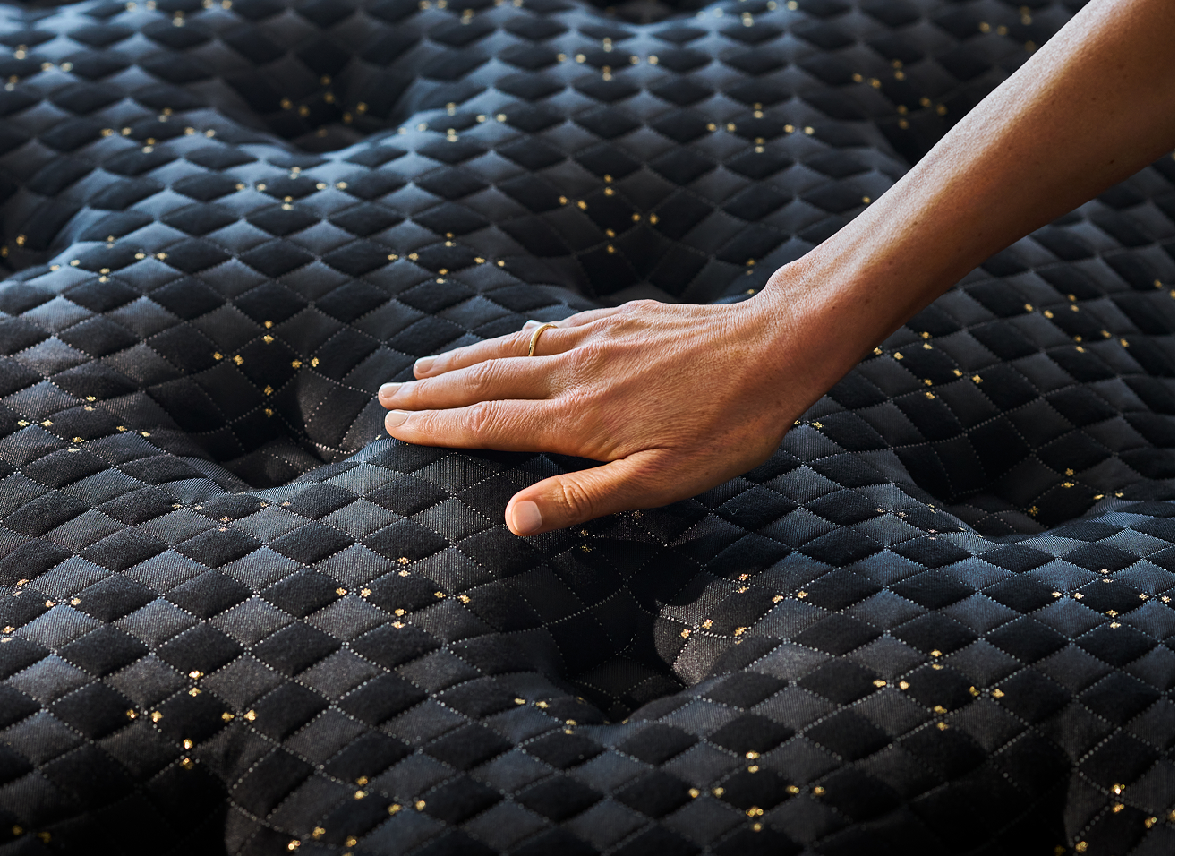 Hand pressing textured black mattress surface