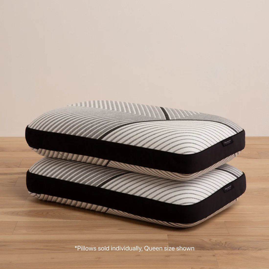 Stacked queen-size striped pillows on wood floor