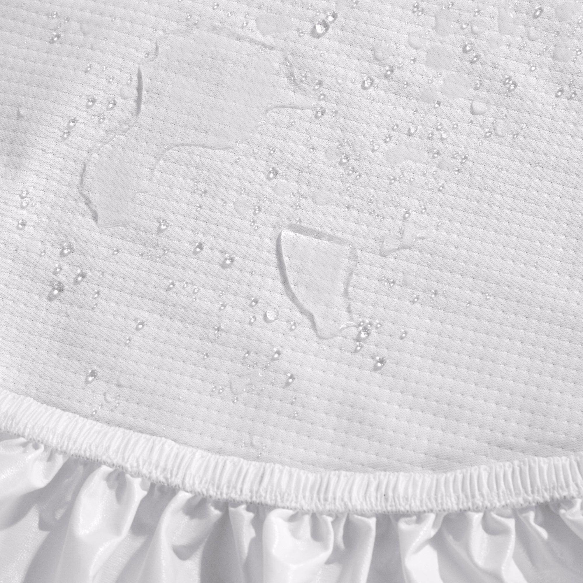 Close-up of a Beautyrest mattress protector with water droplets beading on top and a ruffled elastic hem at the bottom.