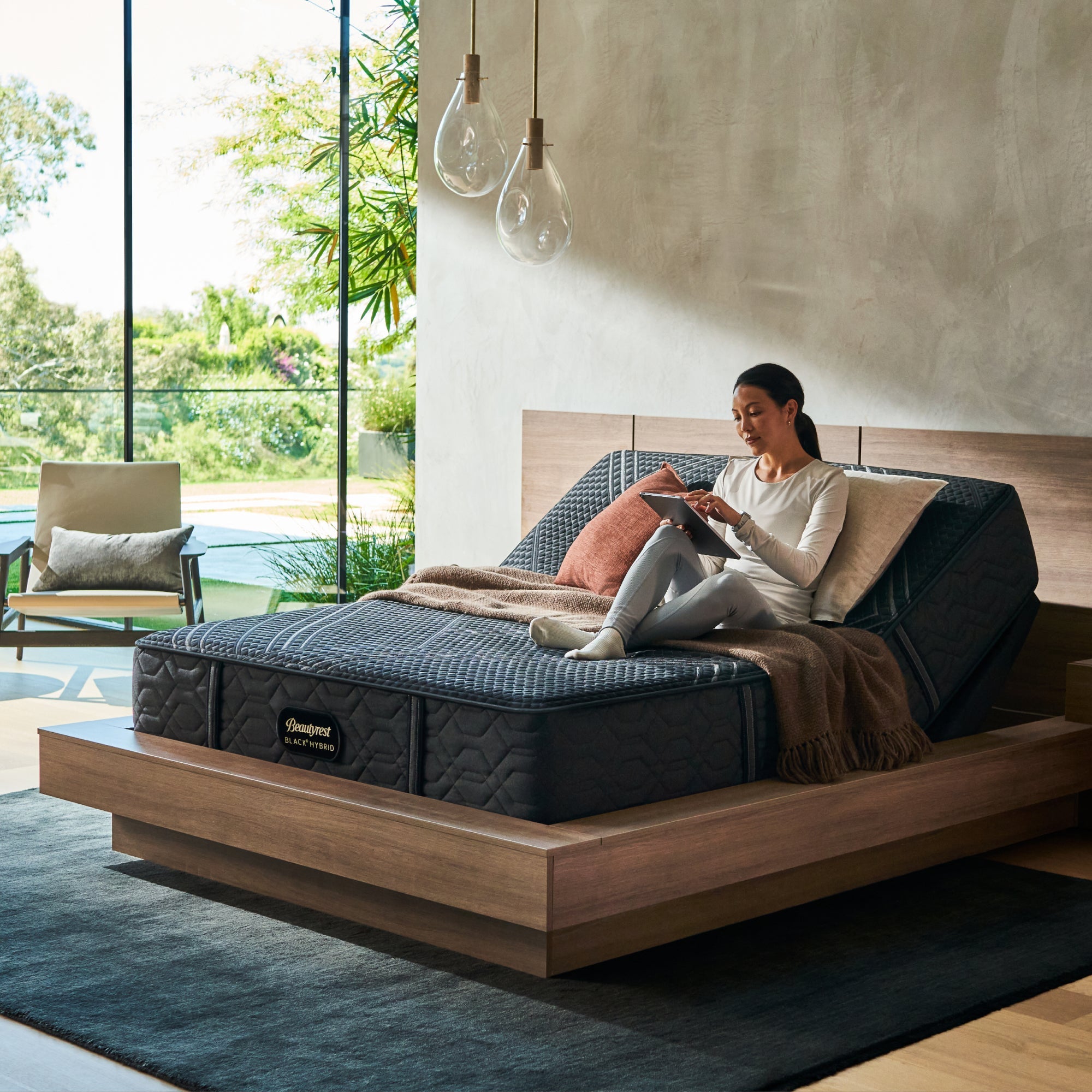 Woman sitting on BeautyRest Medium Hybrid mattress sitting on an adjustable base || series: Series One || feel: Medium