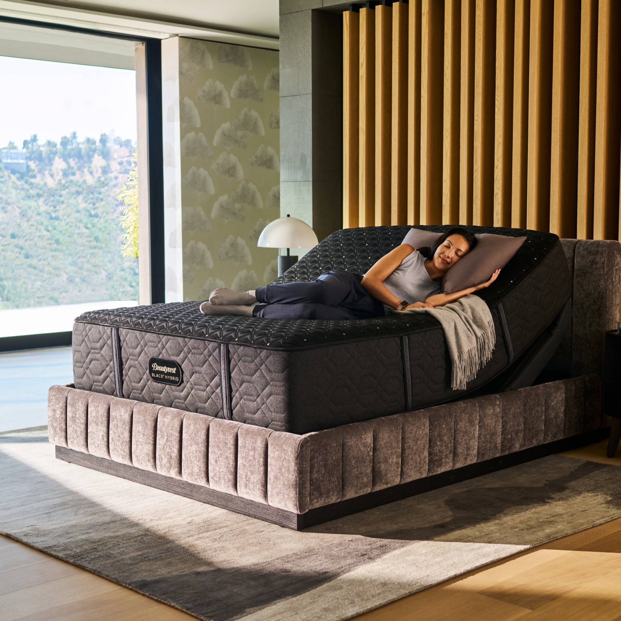 A woman laying on a BeautyRest Plush Hybrid mattress sitting on an adjustable base || series: Series Three || feel: Plush