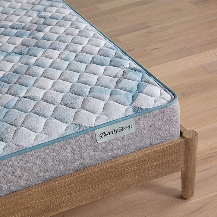 Beautysleep by Beautyrest mattress Gray quilted mattress on a wooden bed frame with 'BeautySleep' branding.